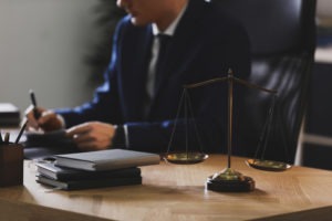 a lawyer writing at his desk next to the scales of justice