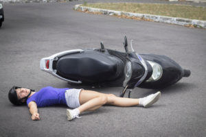 person lying on the ground next to their motorcycle
