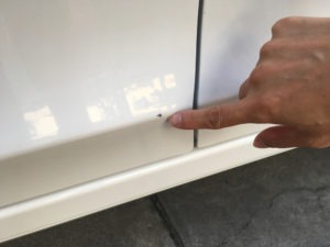 finger pointing to chipped car paint